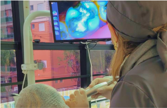 Doutora Ivani usando uma camera intra oral no paciente mostrando a ele em tempo real como estão seus dentes e falando o que se deve ou não fazer.