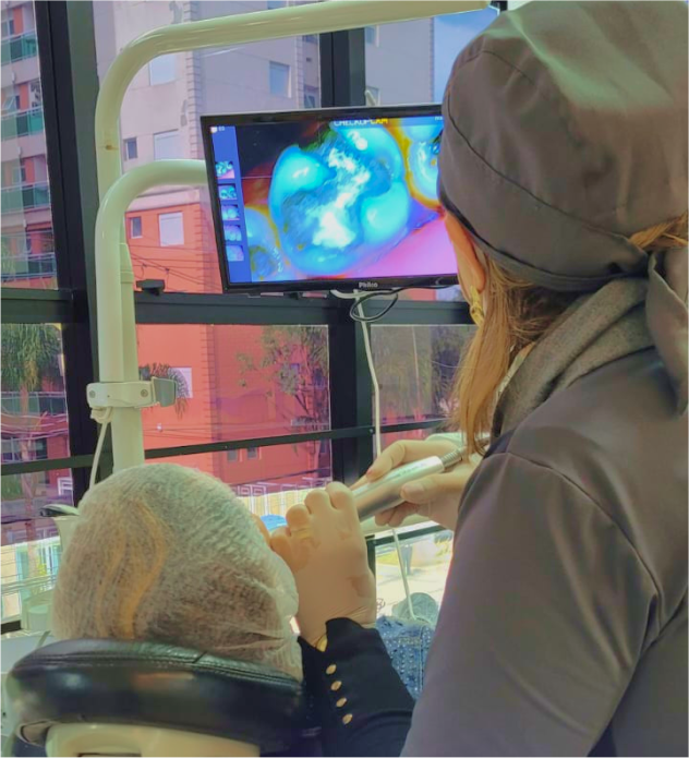 Doutora Ivani usando uma camera intra oral no paciente mostrando a ele em tempo real como estão seus dentes e falando o que se deve ou não fazer.