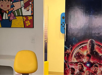 Doutora Adrielly chamando a paciete criança para entrar no consultório, enquano outros pacientes e seus pais aguardam na sala de espera infantil